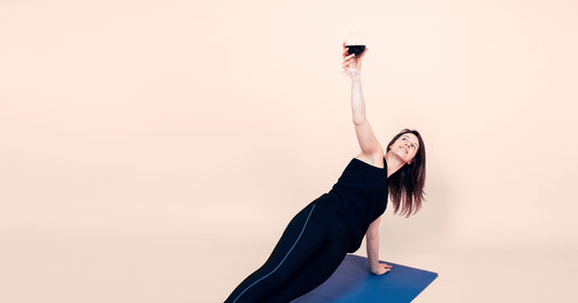 woman holding a glass of red wine while performing yoga