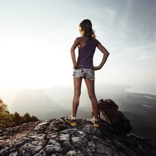 a woman stands at the top of mountain