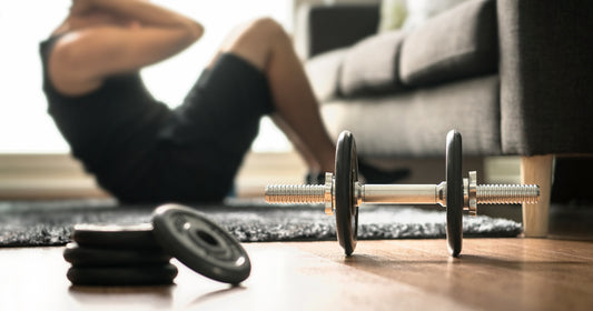a man with dumbbell is sitting up at home