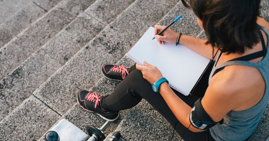 an exercising woman is writing journal